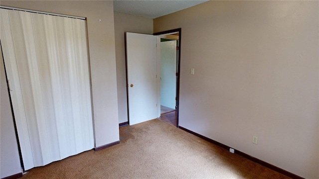 unfurnished bedroom with carpet, a closet, and baseboards