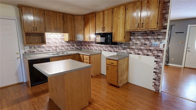kitchen featuring a sink, backsplash, black appliances, and a kitchen island