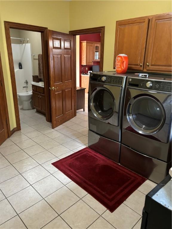 laundry area with separate washer and dryer, cabinet space, and light tile patterned floors