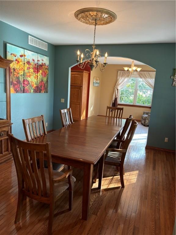 dining space with visible vents, hardwood / wood-style flooring, and a notable chandelier