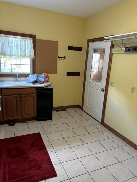 kitchen with dishwasher, baseboards, light countertops, a sink, and light tile patterned floors
