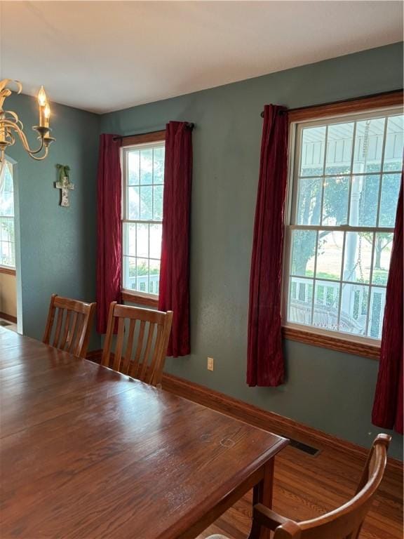 dining space featuring visible vents, wood finished floors, and a chandelier