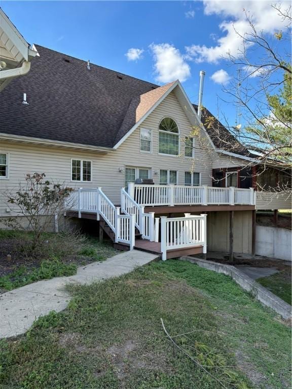 back of property with a lawn, a wooden deck, and a shingled roof