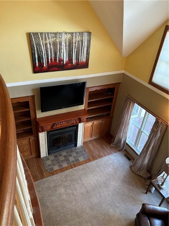 unfurnished living room with a fireplace with flush hearth, wood finished floors, and vaulted ceiling