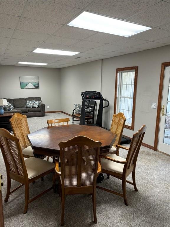 dining room with baseboards, light colored carpet, and a drop ceiling