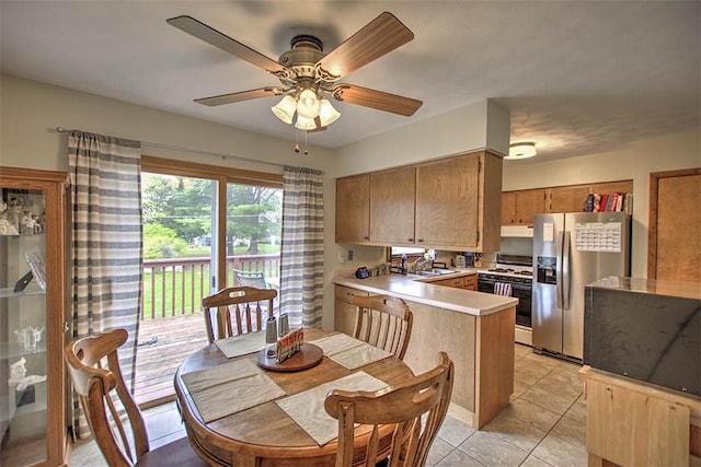 kitchen with a peninsula, a sink, stainless steel fridge with ice dispenser, light countertops, and white range with gas stovetop