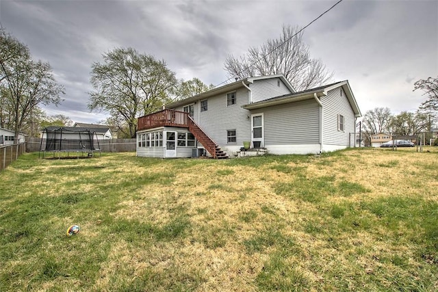 rear view of house with a fenced backyard, a wooden deck, stairway, and a trampoline