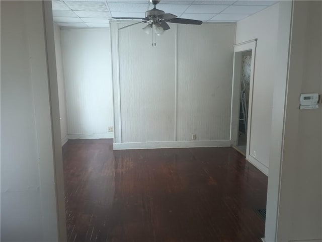 spare room with dark hardwood / wood-style flooring, ceiling fan, and a paneled ceiling