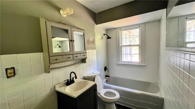 full bathroom featuring toilet, vanity, tile walls, and tiled shower / bath