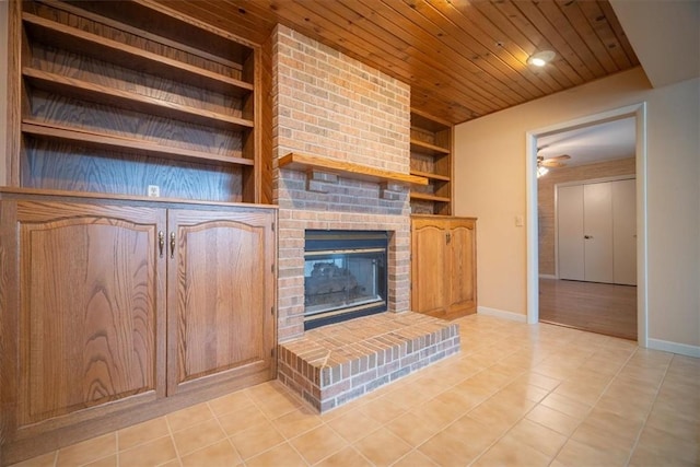 unfurnished living room featuring ceiling fan, wooden ceiling, a brick fireplace, built in features, and light tile patterned floors