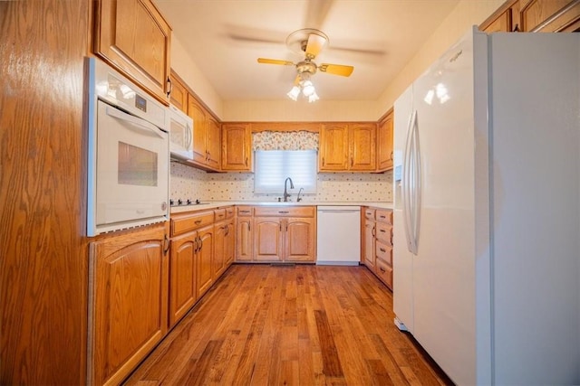 kitchen with ceiling fan, sink, light hardwood / wood-style flooring, white appliances, and decorative backsplash