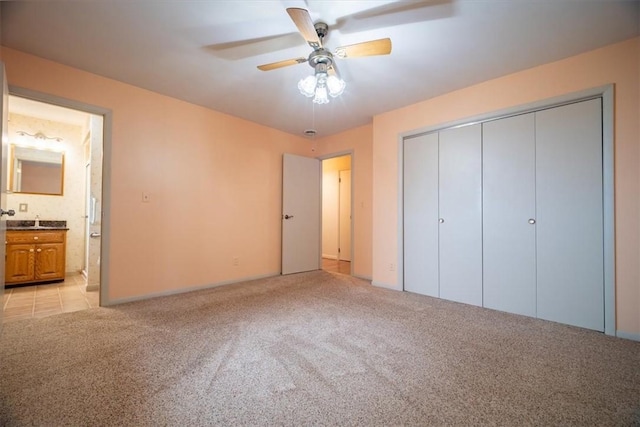 unfurnished bedroom featuring ensuite bath, ceiling fan, a closet, and light carpet