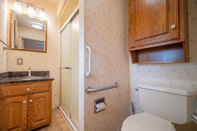 bathroom featuring tile patterned floors, vanity, a shower with shower door, and toilet