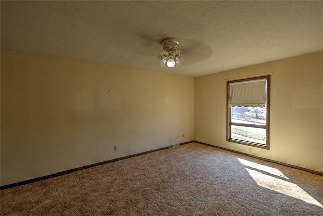 empty room with visible vents, baseboards, carpet, a textured ceiling, and a ceiling fan