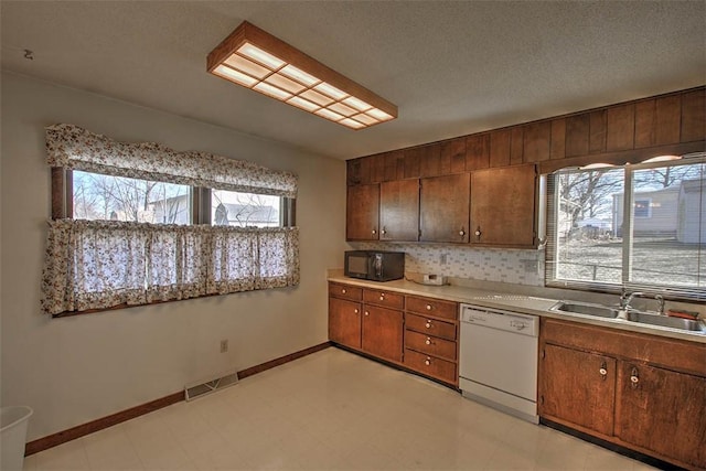 kitchen featuring visible vents, a sink, black microwave, white dishwasher, and light floors