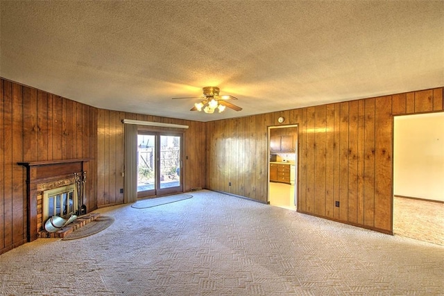 unfurnished living room featuring a ceiling fan, a textured ceiling, a glass covered fireplace, and carpet flooring