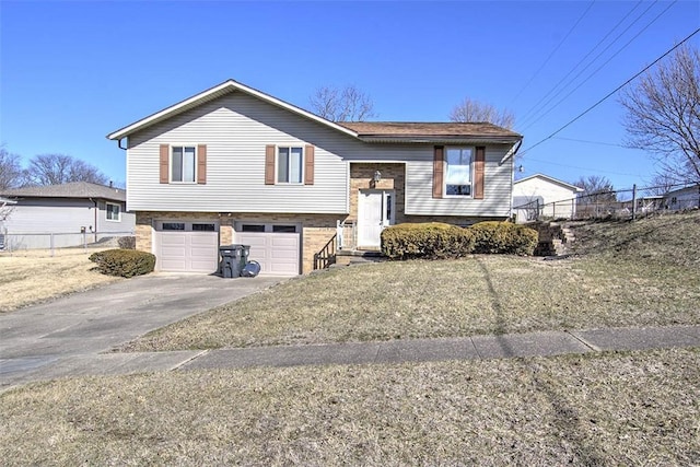 raised ranch with an attached garage, concrete driveway, and fence