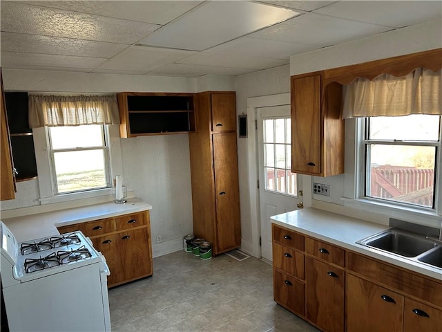 kitchen featuring a sink, brown cabinets, white gas range oven, and light floors