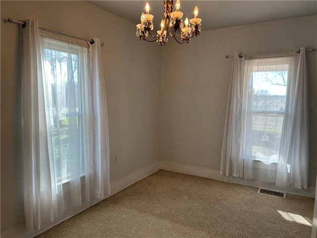 unfurnished room with a wealth of natural light, visible vents, baseboards, and a chandelier