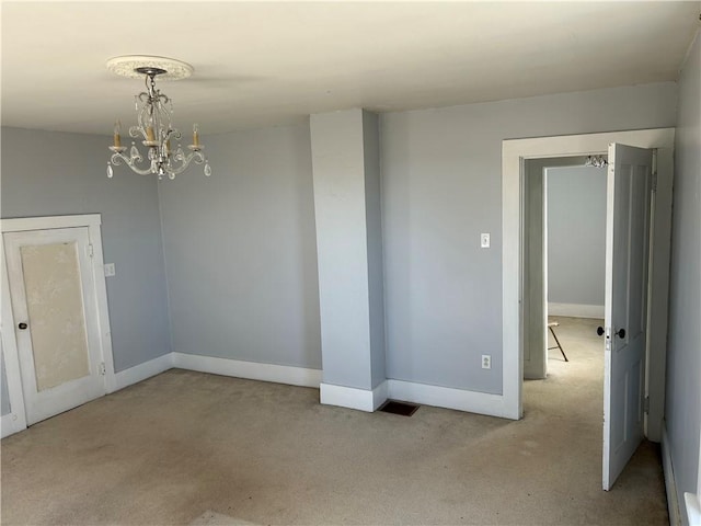 unfurnished room featuring baseboards, carpet flooring, and a chandelier