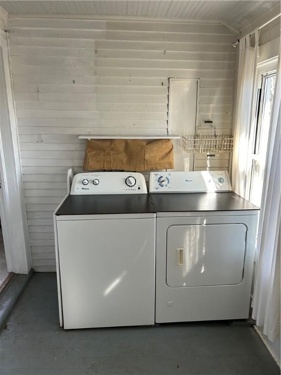 washroom with wooden walls, washer and dryer, and laundry area