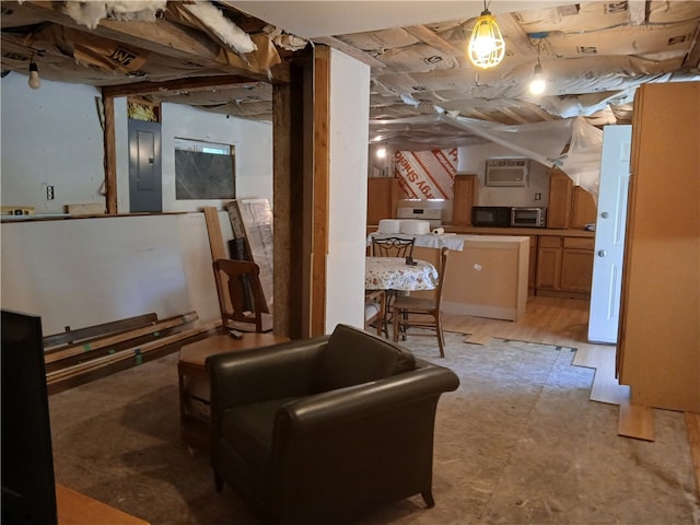 basement featuring a wall mounted air conditioner, electric panel, and light hardwood / wood-style flooring