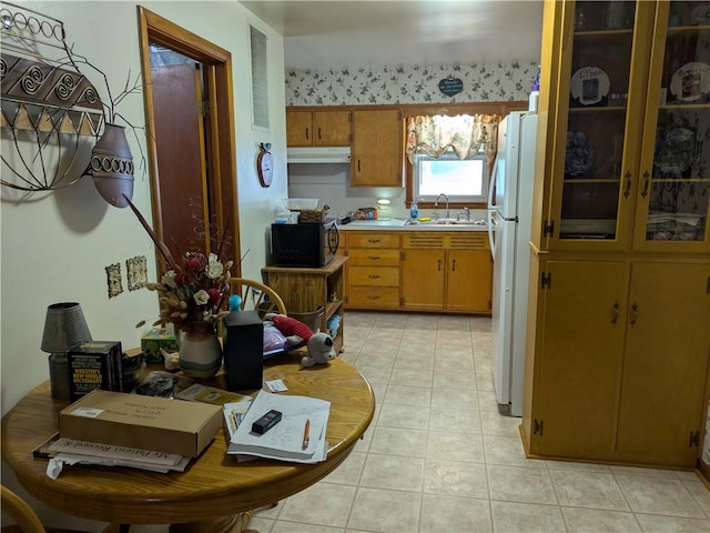 409 E Adams St, Paris, IL 61944 - kitchen with freestanding refrigerator, light countertops, a sink, brown cabinetry, and light tile patterned floors