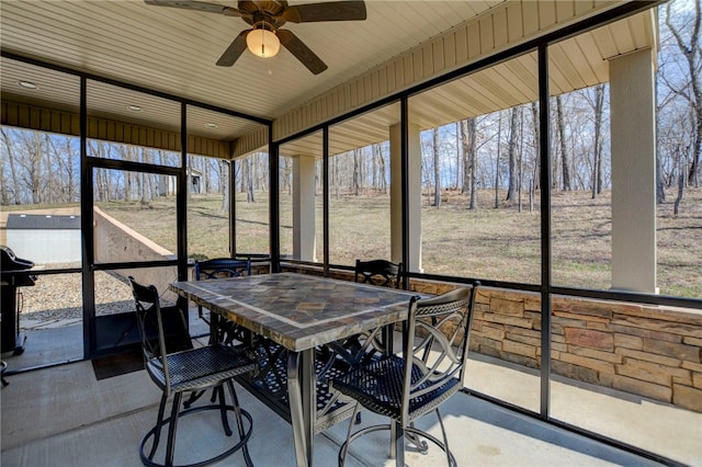 sunroom / solarium featuring a healthy amount of sunlight, outdoor dining space, and a ceiling fan