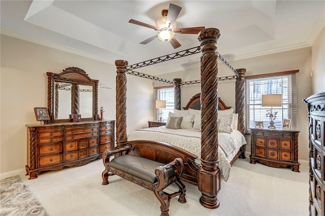 carpeted bedroom featuring ornamental molding, a tray ceiling, and baseboards