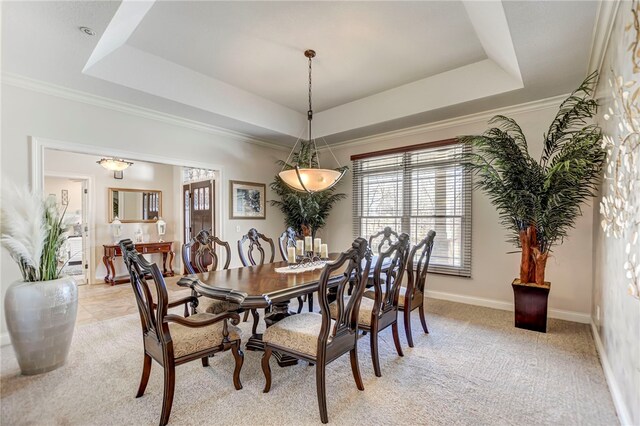 dining space with baseboards, a tray ceiling, and light carpet