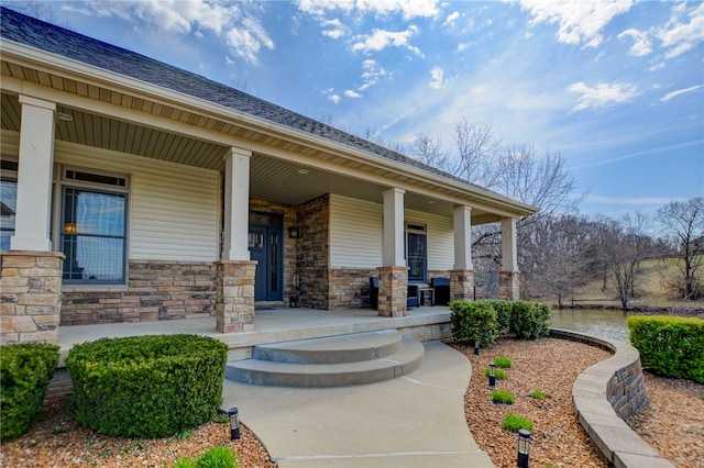 doorway to property featuring stone siding and a porch