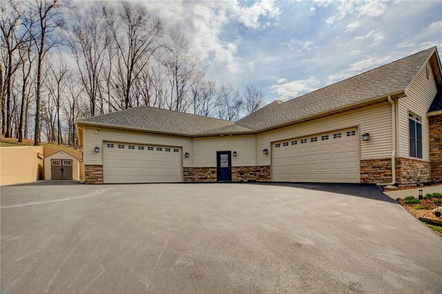 view of front of house with roof with shingles, stone siding, a garage, and aphalt driveway