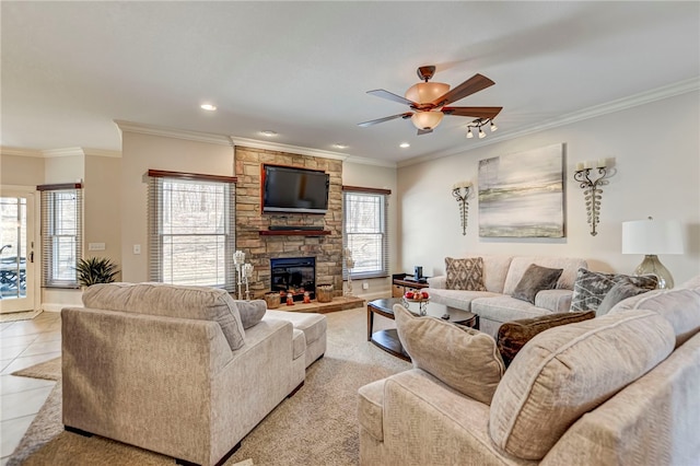 living room with light tile patterned flooring, a stone fireplace, crown molding, and ceiling fan