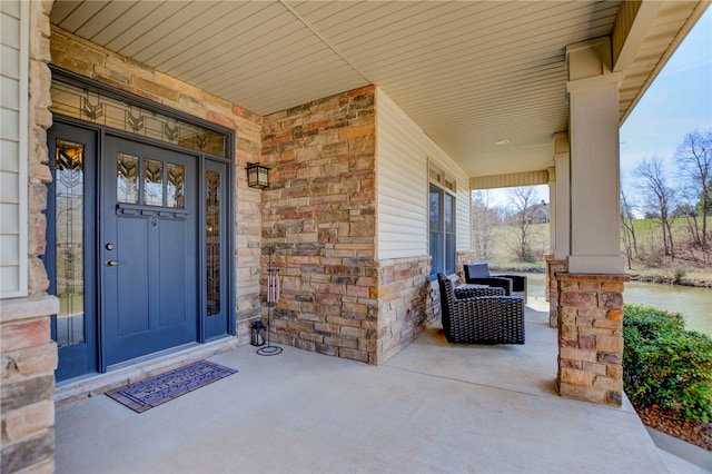 property entrance featuring covered porch and stone siding