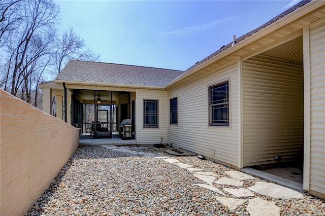 rear view of house with a shingled roof and a sunroom