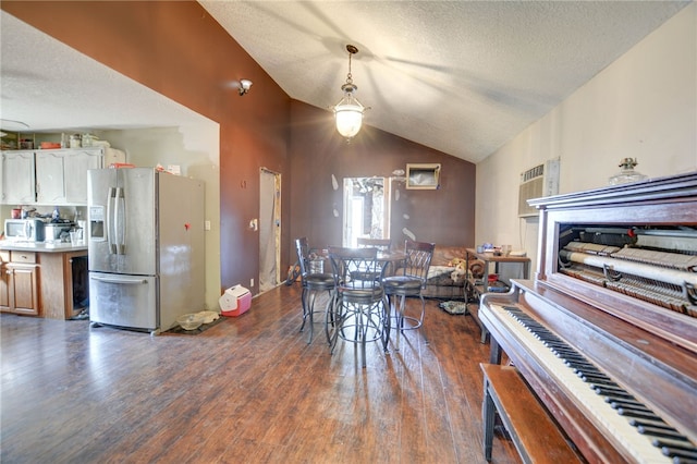 dining room featuring dark hardwood / wood-style floors, a textured ceiling, and vaulted ceiling