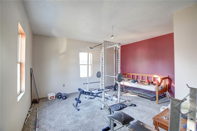 exercise area with a textured ceiling, carpet floors, and a healthy amount of sunlight