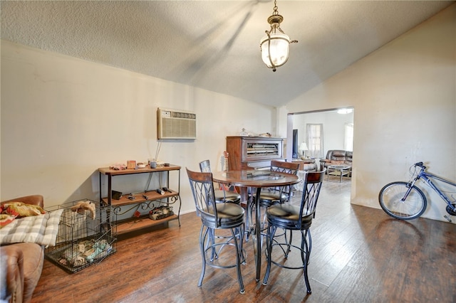 dining room featuring hardwood / wood-style flooring, a wall mounted air conditioner, lofted ceiling, and a textured ceiling