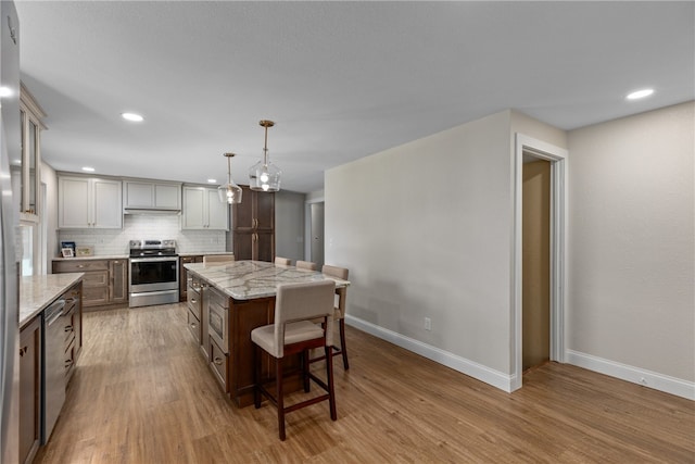 kitchen featuring a breakfast bar, a center island, stainless steel appliances, and light wood-type flooring