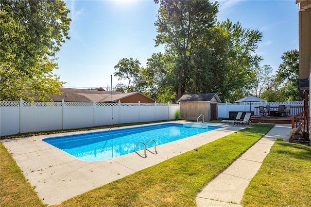 view of swimming pool featuring a yard, a deck, a shed, and a patio area