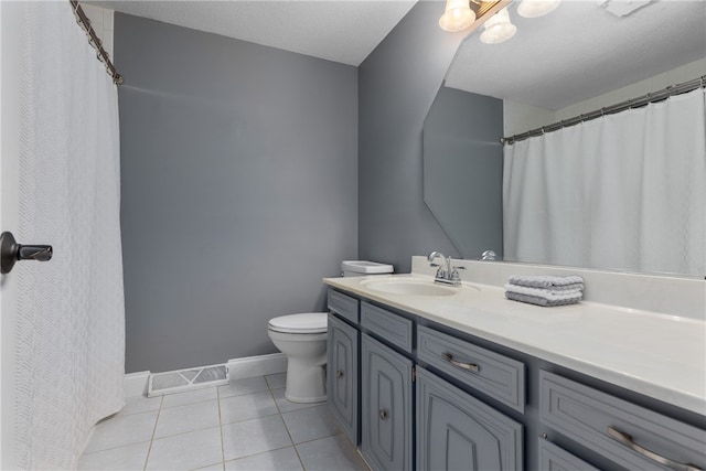 bathroom featuring tile patterned flooring, vanity, toilet, and a textured ceiling