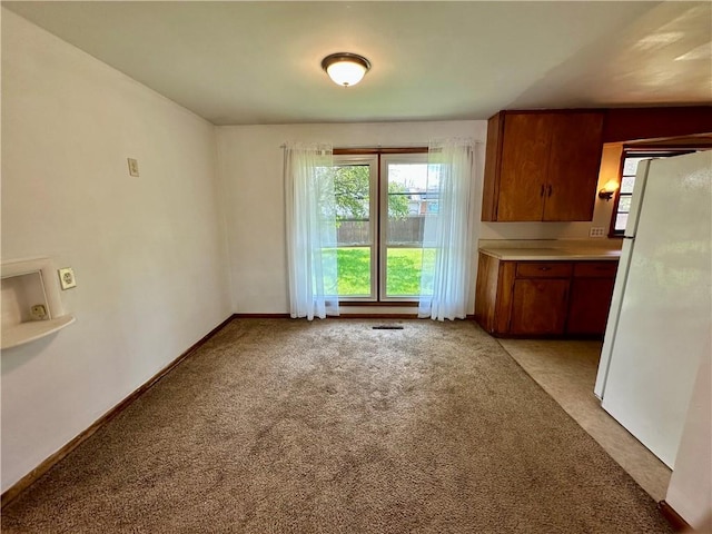 1321 Rudy Ave, Mattoon, IL 61938 - kitchen featuring freestanding refrigerator, light carpet, brown cabinets, and light countertops
