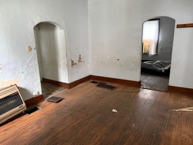 905 N Griffin St, Danville, IL 61832 - unfurnished living room featuring heating unit, hardwood / wood-style flooring, arched walkways, and baseboards