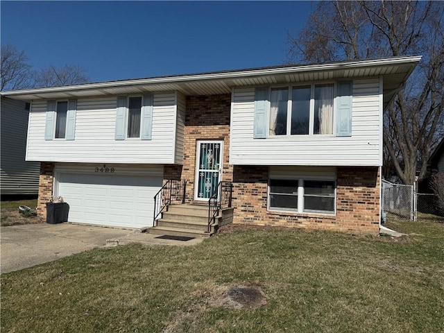 raised ranch with brick siding, a garage, concrete driveway, and a front lawn