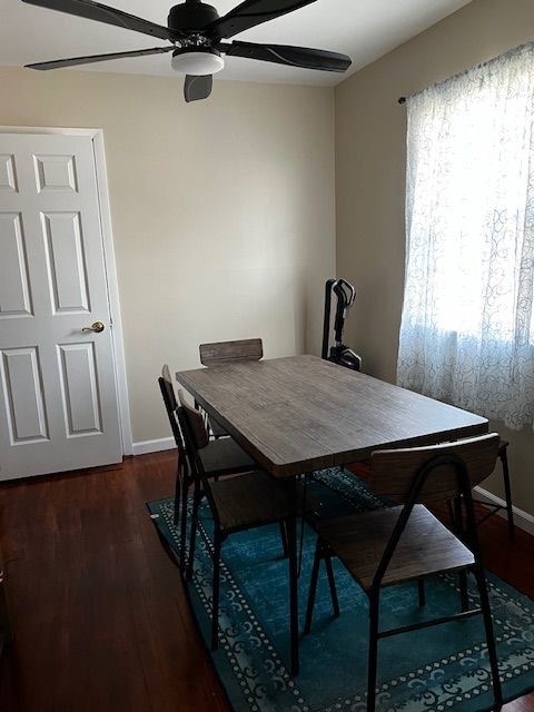 dining area with ceiling fan and dark wood-type flooring