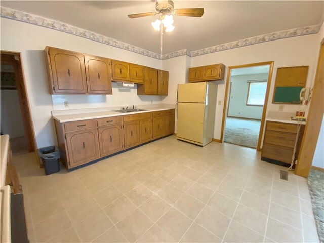 828 S Indiana St, Ashmore, IL 61912 - kitchen with freestanding refrigerator, light countertops, brown cabinets, and ceiling fan