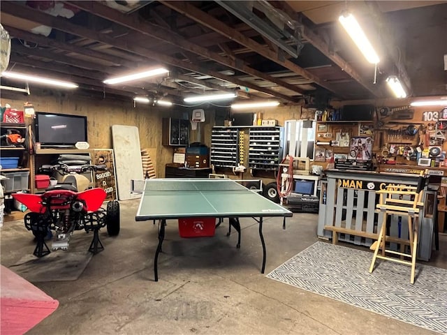 game room featuring a workshop area, concrete floors, and wood walls