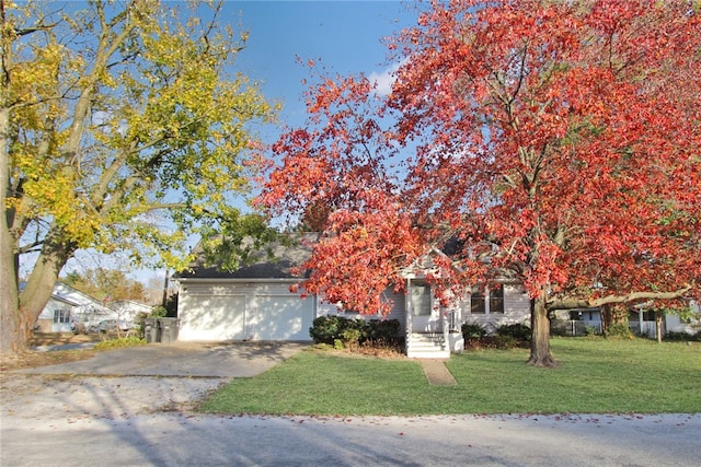 view of property hidden behind natural elements featuring a garage and a front yard