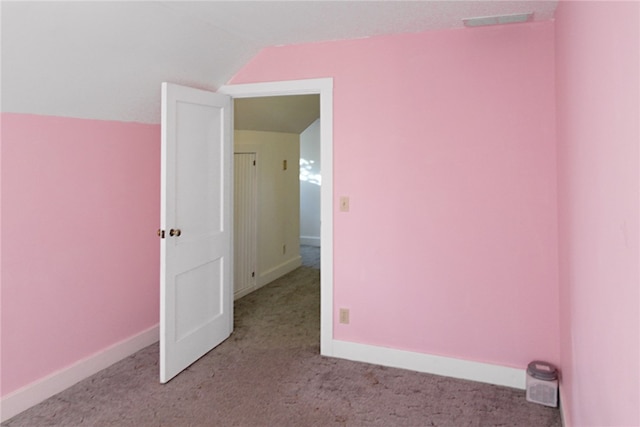 carpeted empty room featuring vaulted ceiling