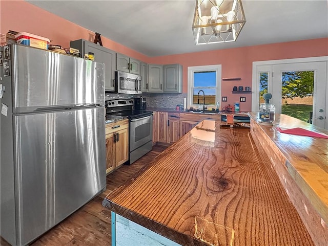 kitchen featuring stainless steel appliances, plenty of natural light, a sink, and dark wood-type flooring